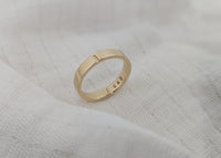 Gold ring with engraved text on a textured white surface