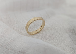 Gold ring with engraved text on a textured white surface
