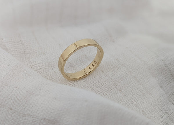 Gold ring with engraved text on a textured white surface