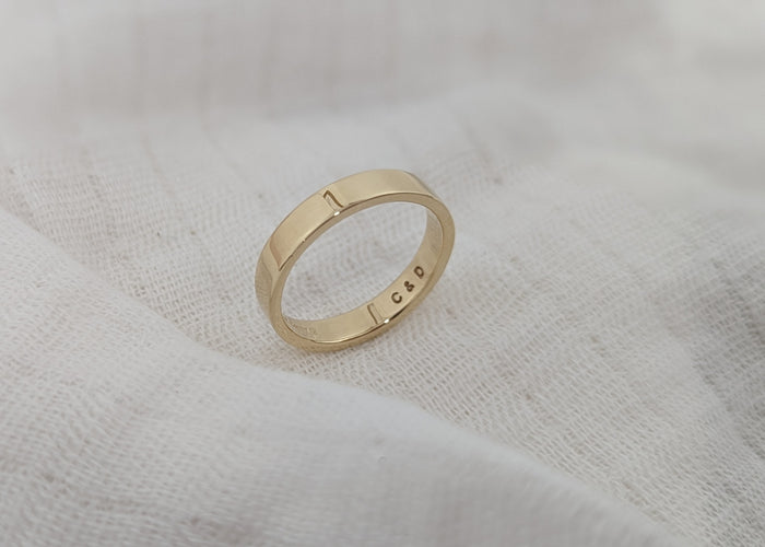 Gold ring with engraved text on a textured white surface